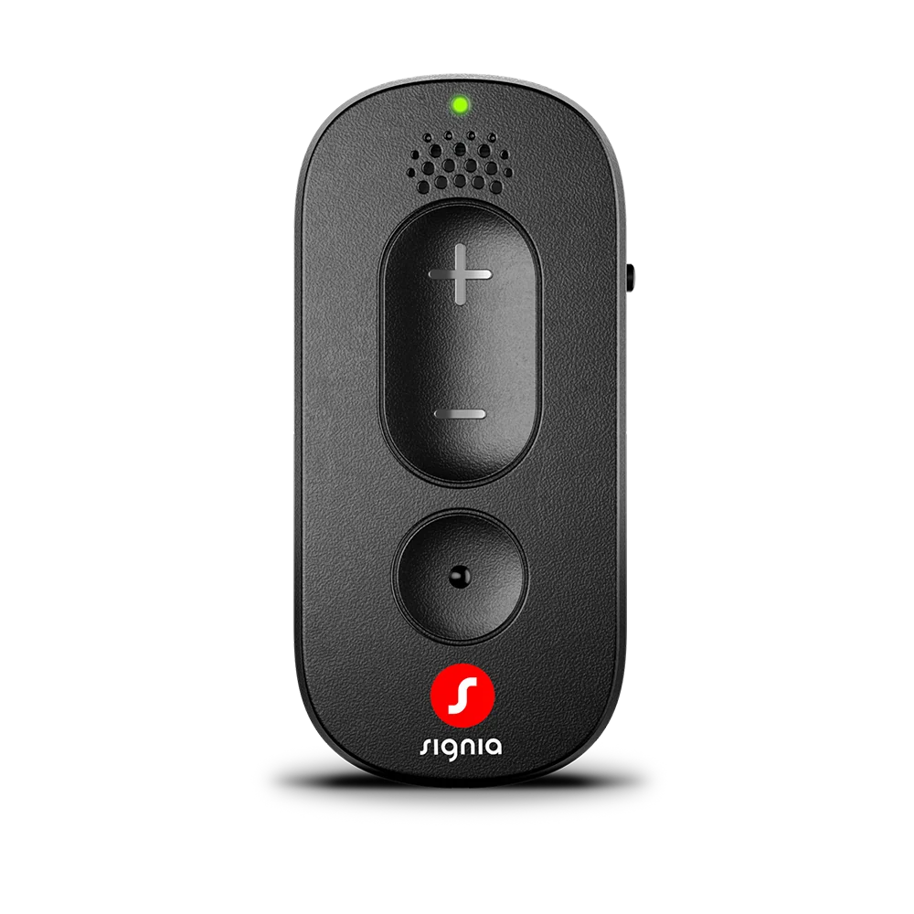 The Signia Remote Control, in black, features plus and minus buttons, a round button positioned below them, a speaker grill at the top, a small green LED light indicator, and the Signia logo at the bottom—all set against a white background.
